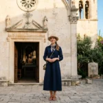Touriste en tenue respectueuse devant une église historique en pierre, un comportement à privilégier à éviter en Croatie.