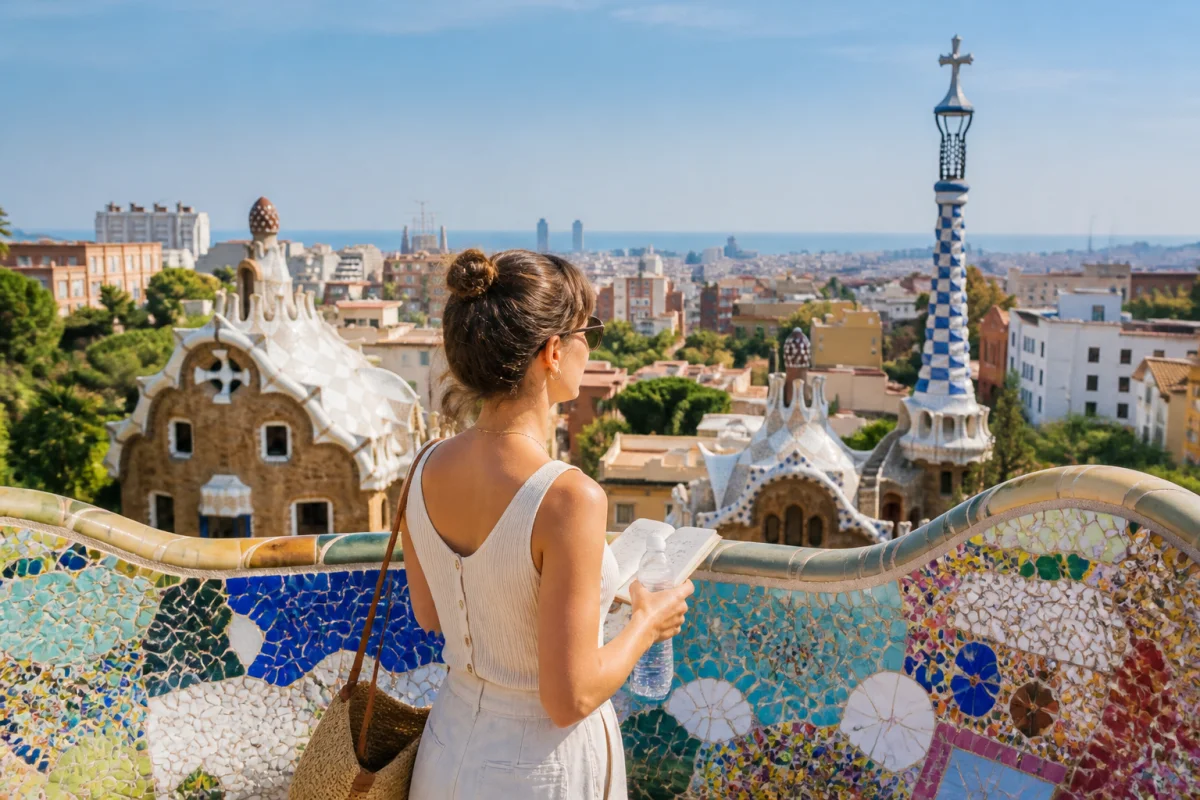 Voyageuse admirant Barcelone depuis une terrasse mosaïquée du parc Güell, avec la mer et la ville en arrière-plan